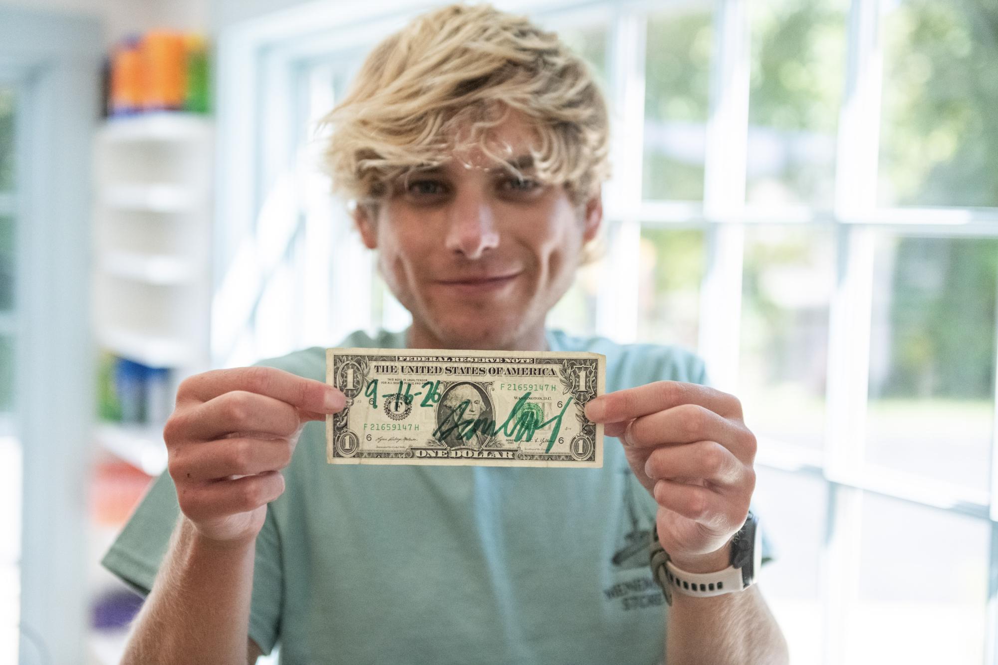 Sam Ebby holds up the first dollar.