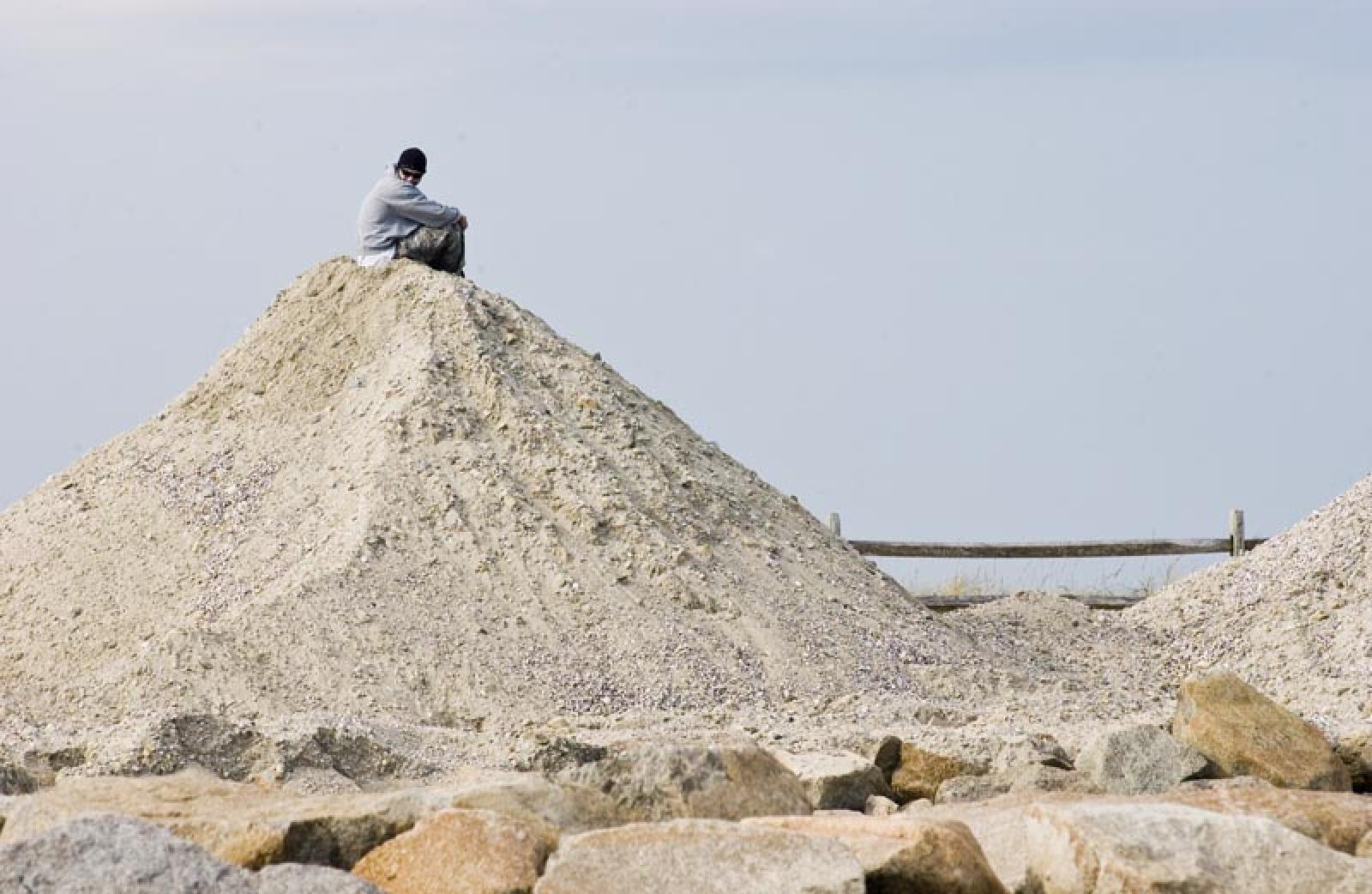mountain of sand with man sitting on top