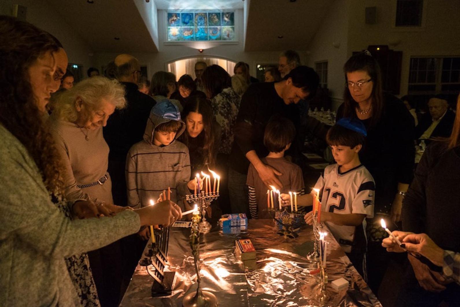 A family gathered around a table to light menorahs during Hanukkah.