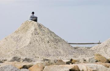 mountain of sand with man sitting on top