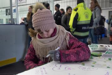 Alison Gatchell, 10, of Oak Bluffs writes a note for Mike Hathaway during public skate fundraiser.