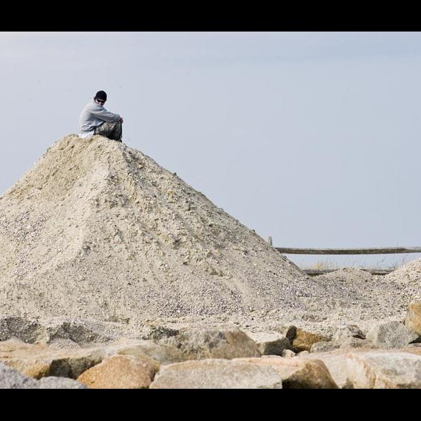 mountain of sand with man sitting on top