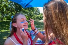 Lily Trimmer, 13, of Aquinnah and Greenwich, Conn., applies paint on the face of Ruby Schiller, 14, of Aquinnah and Cambridge.