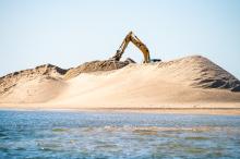 Large pile of sand from dredge lies on the barrier beach.