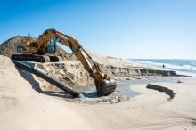 Excavator digs up sand from dredge.