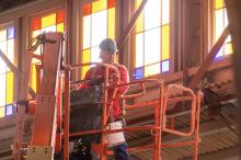 A worker inspects progress up by the stained glass.