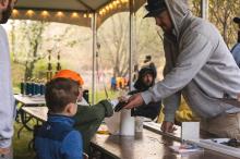 Cooper Ferson (right) helps some young fishermen measure their catch.