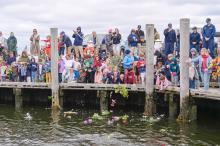 Chilmark school students throw their flowers in the harbor.