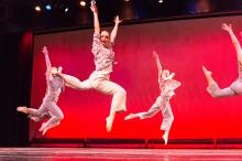 Dancers leap in time to the music.