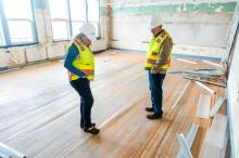 [l-r] Amy Houghton, Mike Watts remark on the sorry state of the warped wooden floorboards.