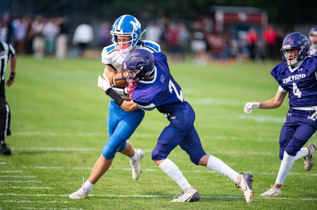Vineyard player makes a tackle along the sideline.