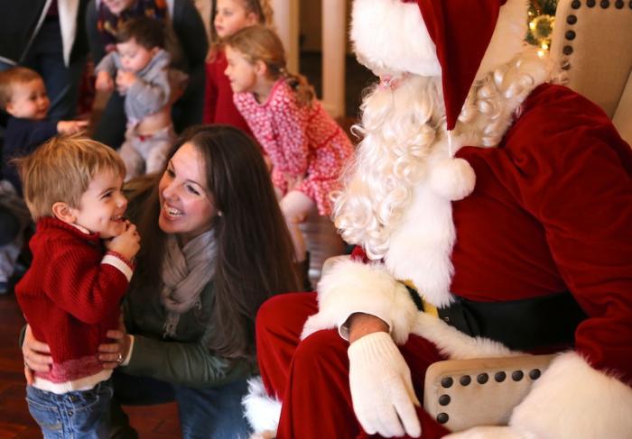 Ty Arieta, two and a half, meets Santa at the Kelley House as his mother Alexa looks on.