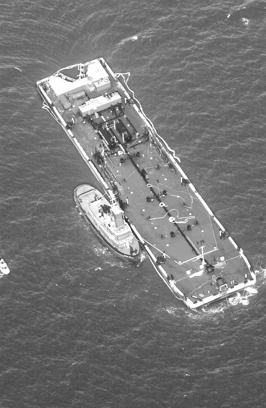 Stricken barge was surrounded by booms, and oil from its leaking single hull was offloaded.