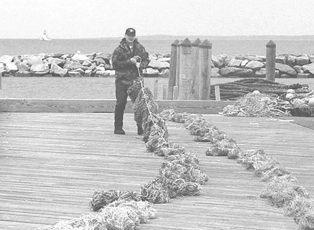 Tribal Ranger Jeff Day helps deploy special absorbent boom materials in Menemsha harbor.