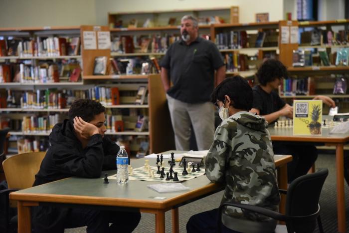 Coach TJ Reap (background) keeps an eye on his team, as Calebe Dos Santos (far left) ponders his next move.