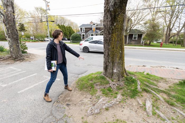 Emily Ellingson shows the problems with a tree's roots near the Alley's General Store parking lot.