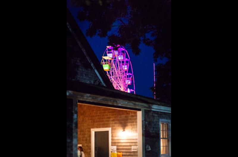 The multicolored Ferris wheel peeks out behind the barn.
