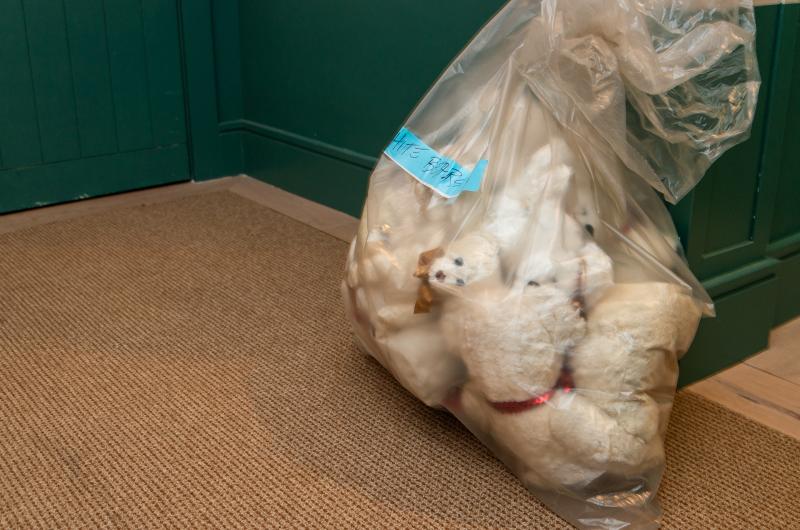 A bag of white smaller bears waits in the hallway.