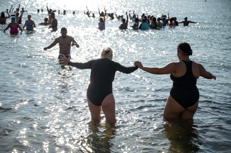 Swimmers help each other enter and exit the water.