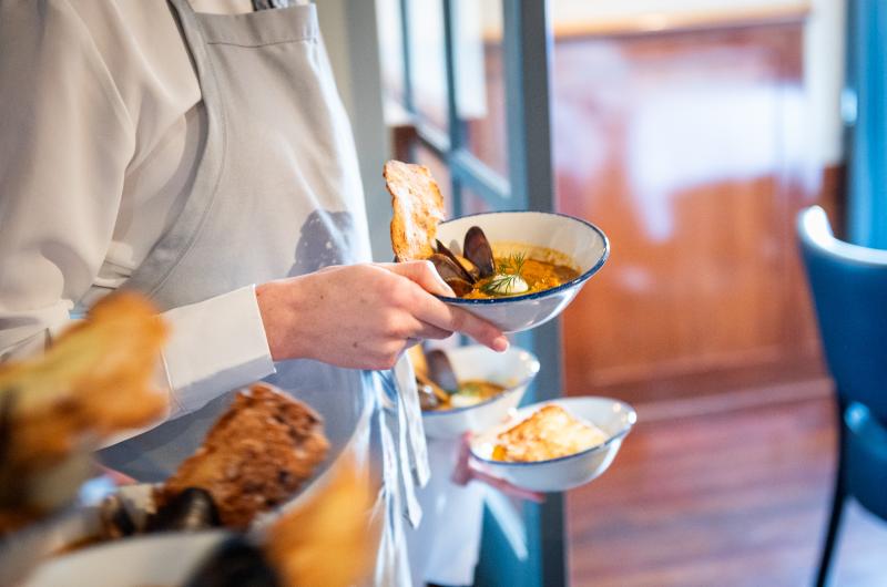 Servers bring out the fire roasted cioppino with smoked mussels.