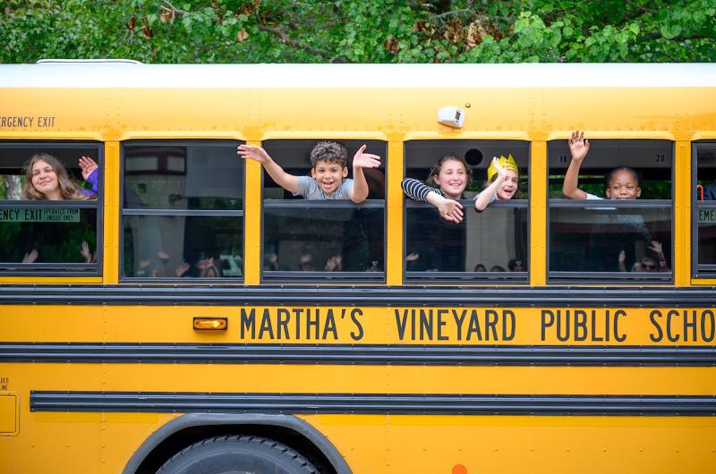 Students wave goodbye from the bus.